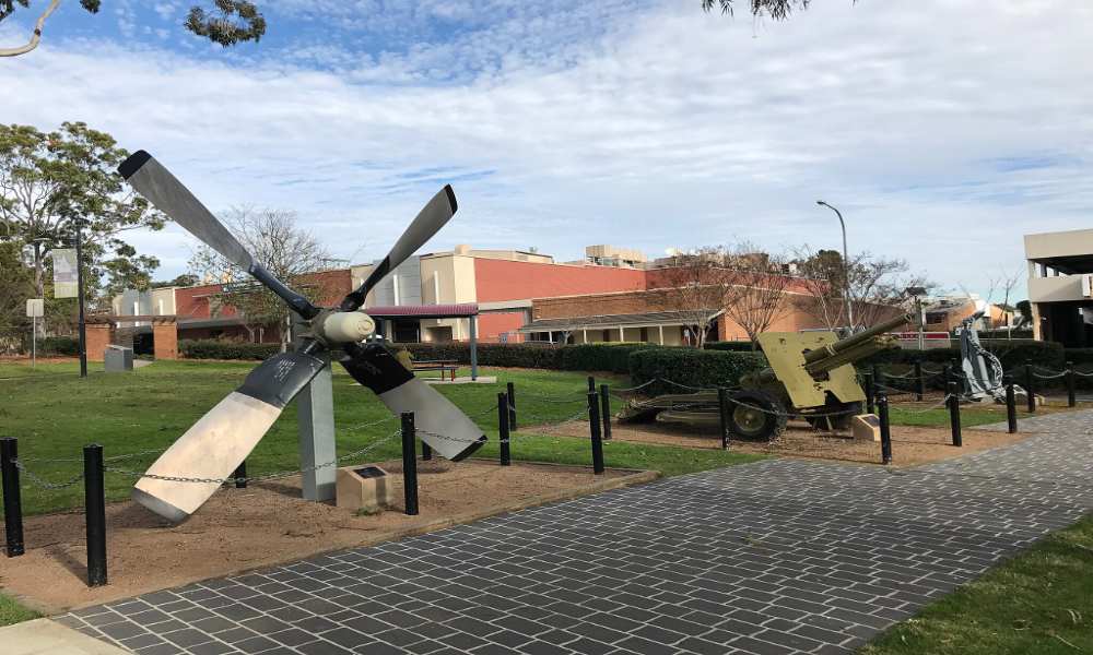 Outdoor display of historical military artifacts including a large aircraft propeller and artillery pieces at Mawson Park, Campbelltown, New South Wales.